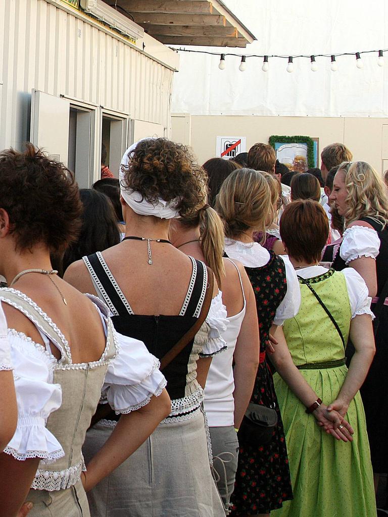 Frauen in einer Warteschlange an einer öffentlichen Toilette.