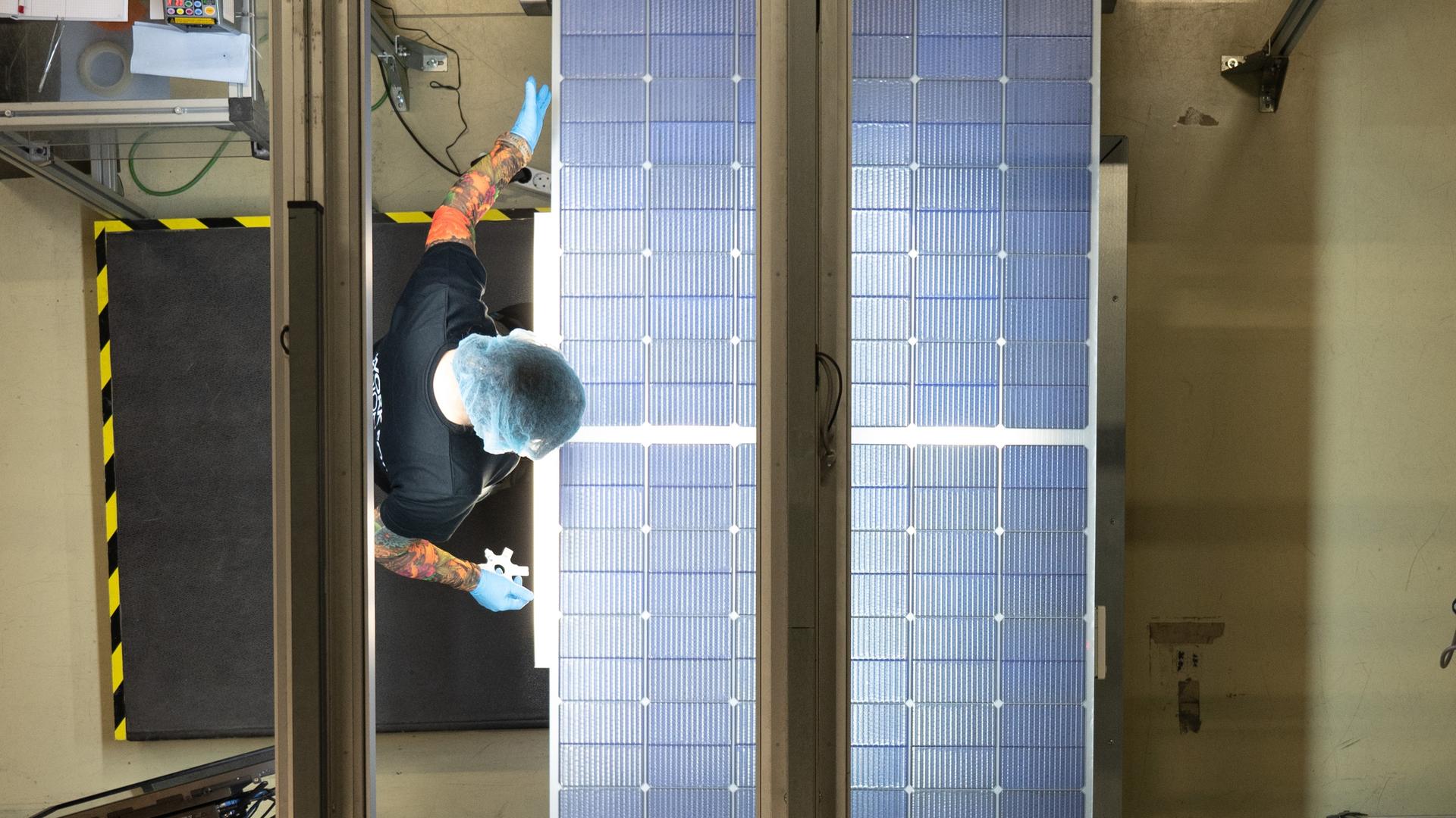 Eine Mitarbeiterin steht bei der Qualitätskontrolle an einer Produktionslinie für Solarmodule im Werk der Meyer Burger Technology AG in Freiberg.