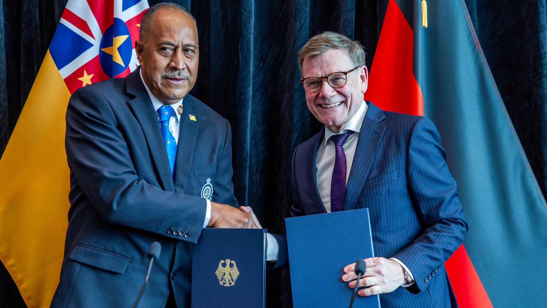 Auckland: Außenminister Wadephul und Dalton Takelage, Premierminister von Niue, reichen sich die Hände und halten Dokumente.