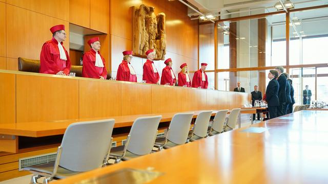 Die Richter und Richterinnen in roten Roben sitzen nebeneinander im großen Saal.