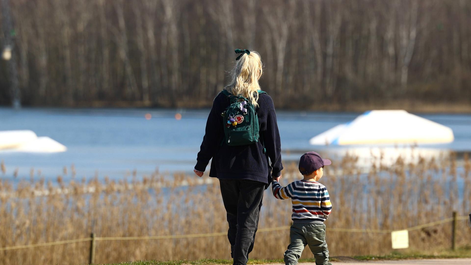 Mutter geht mit Kleinkind durch Park