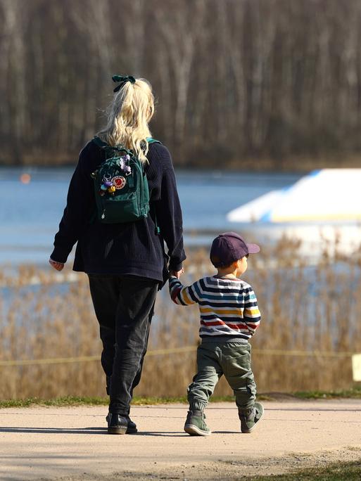 Mutter geht mit Kleinkind durch Park