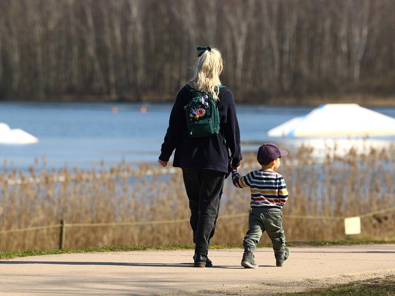 Mutter geht mit Kleinkind durch Park