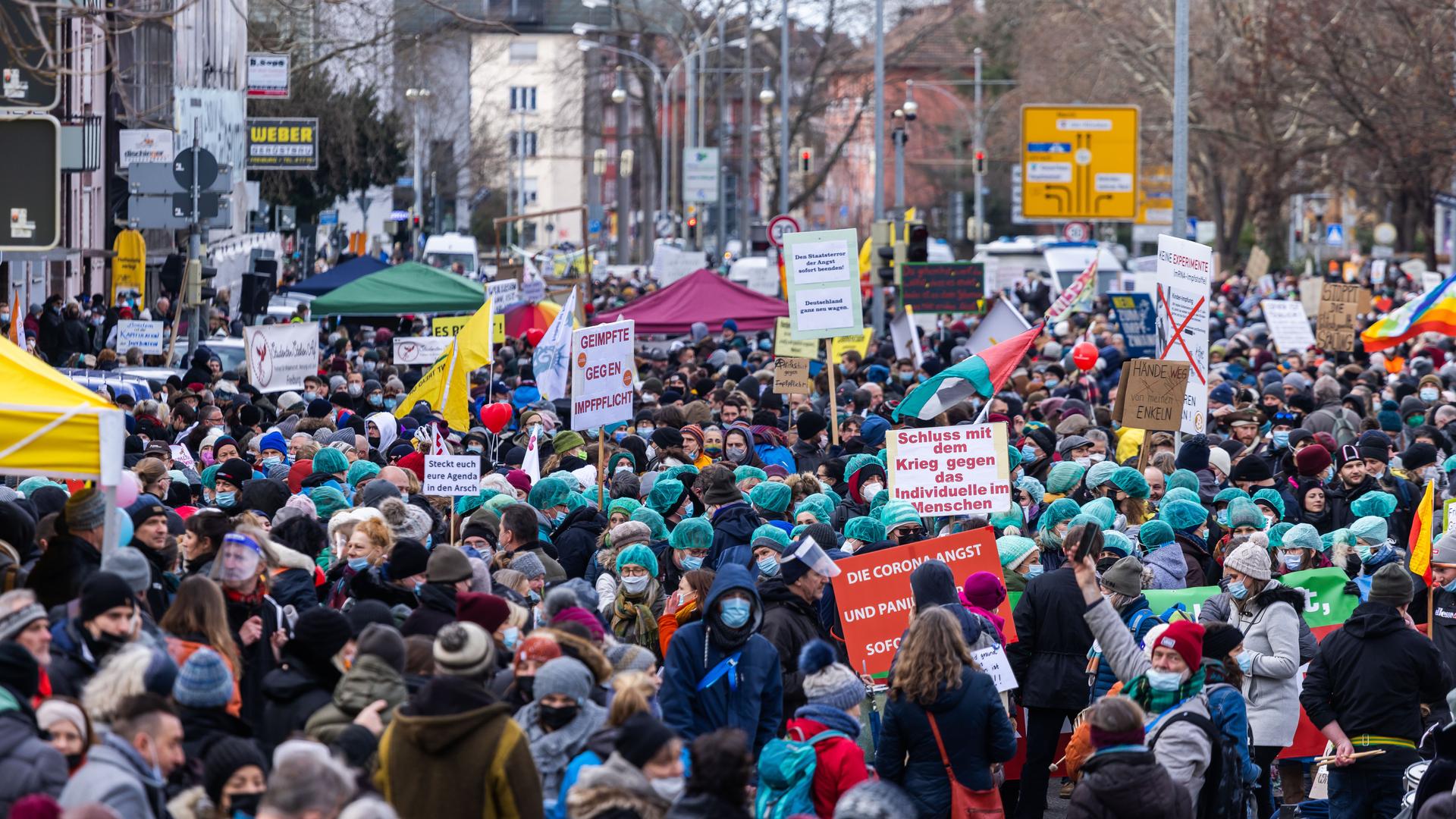 Zahlreiche Teilnehmer einer "Querdenker"-Demonstration stehen mit Plakaten in der Freiburger Innenstadt. 