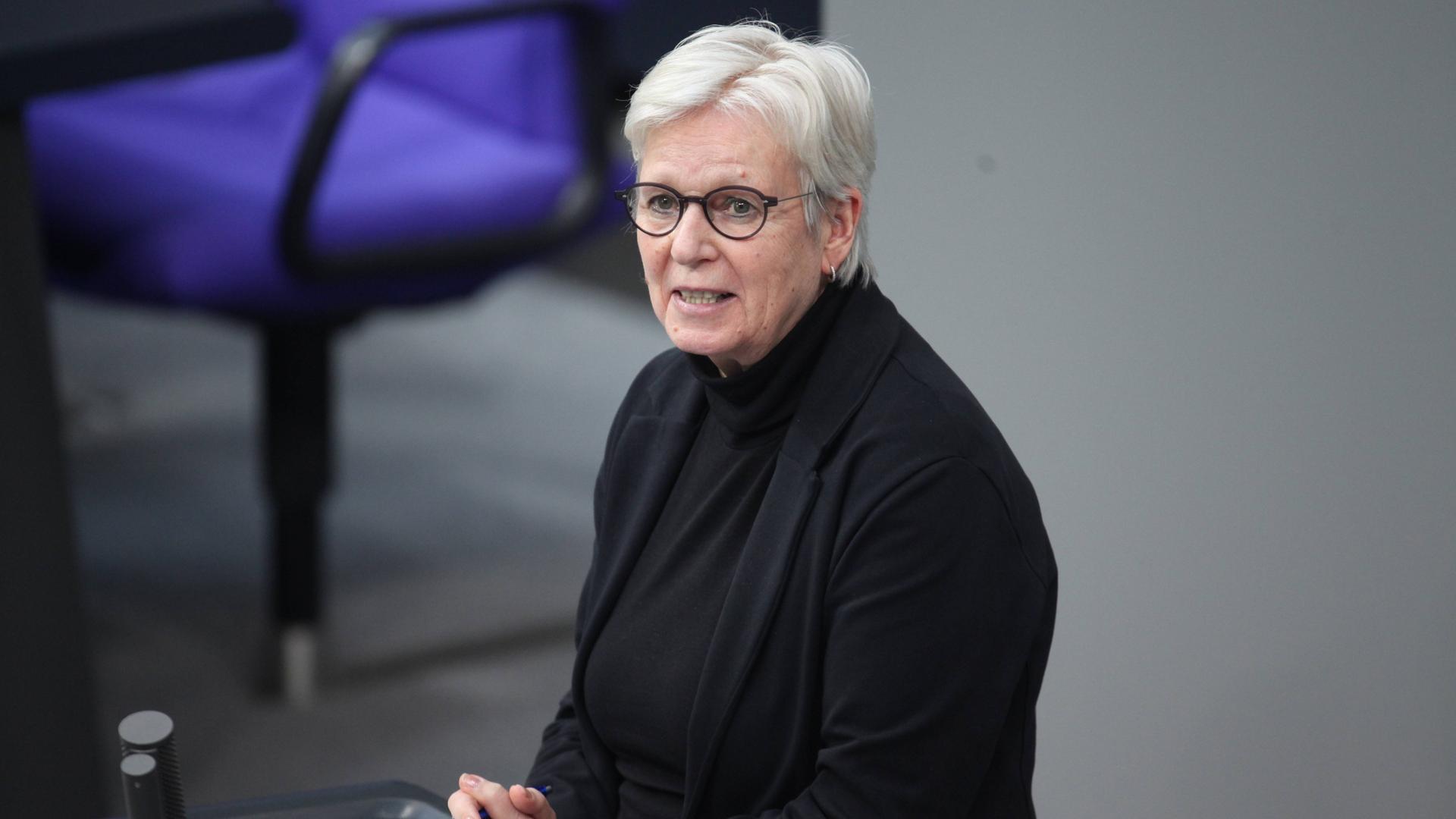 Maria Klein-Schmeink (Bündnis 90/Grüne) während einer Rede im Deutschen Bundestag. Ein Frau mit weißem, kurzem Haar in dunkler Kleidung spricht im Parlament. Sie ist seitlich fotografiert. Maria Klein-Schmeink (Bündnis 90/Grüne) während einer Rede im Deutschen Bundestag. Ein Frau mit weißem, kurzem Haar in dunkler Kleidung spricht im Parlament. Sie ist seitlich fotografiert.