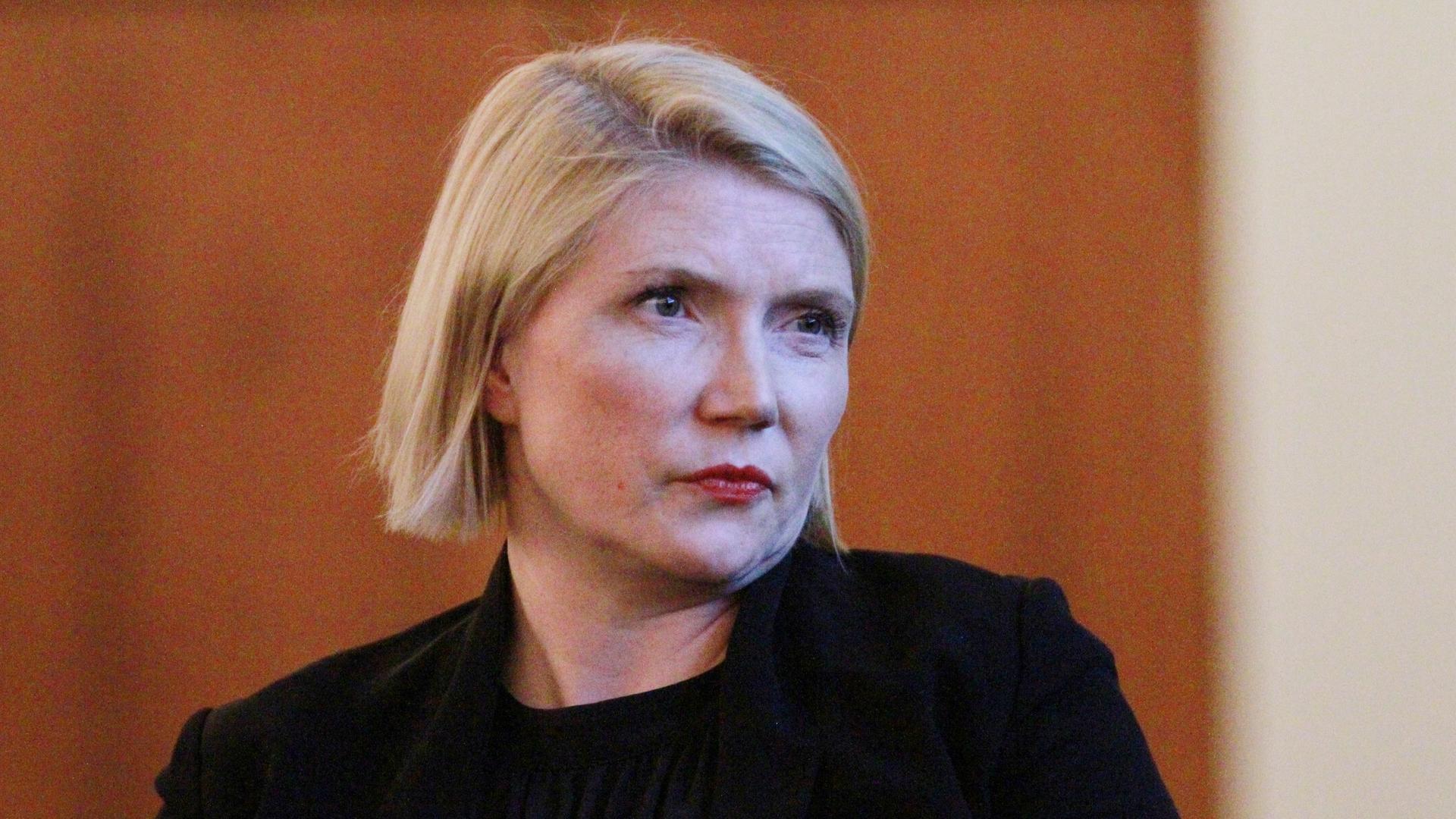 Die Politikwissenschaftlerin Cathryn Clüver Ashbrook (im seitlichen Porträt fotografiert, im Hintergrund eine braune Holzwand).