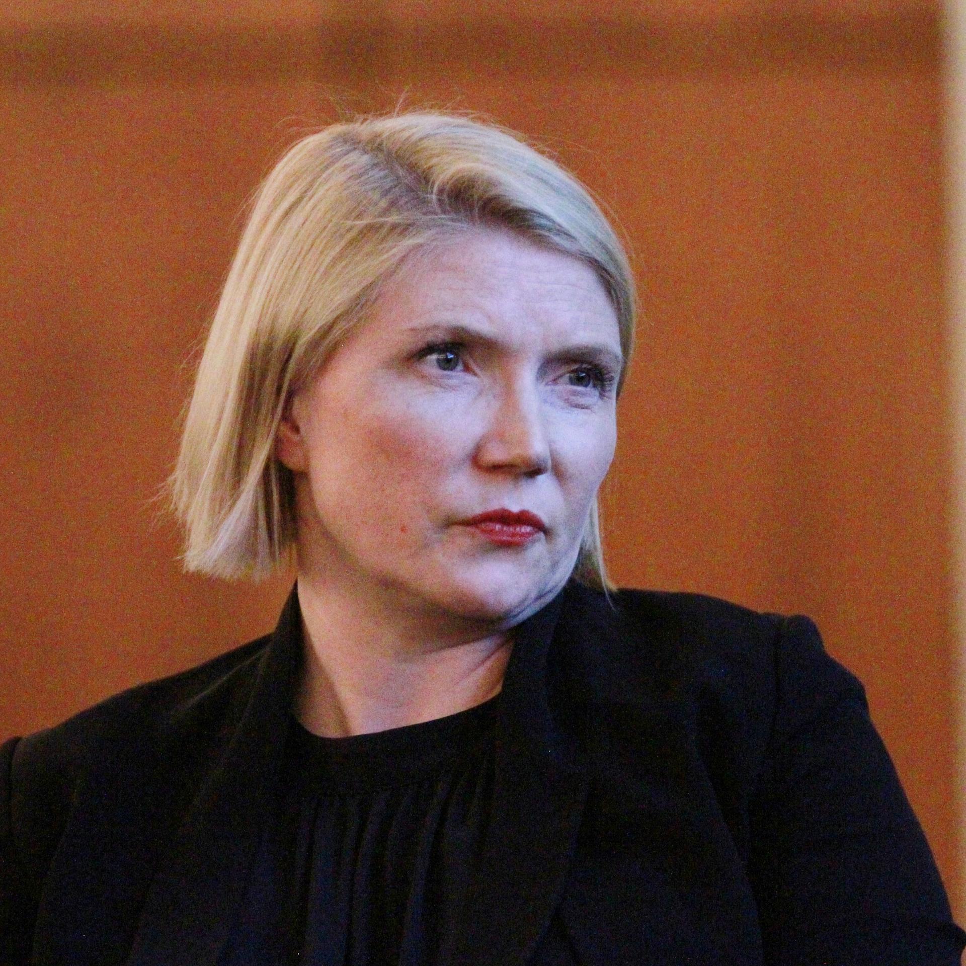 Die Politikwissenschaftlerin Cathryn Clüver Ashbrook (im seitlichen Porträt fotografiert, im Hintergrund eine braune Holzwand).