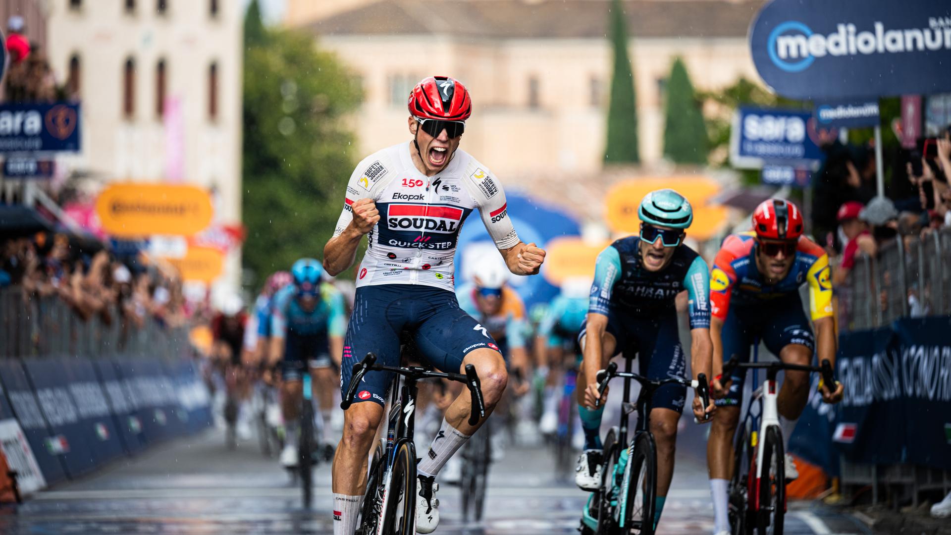 Der Franzose Paul Magnier gewinnt die 18. Etappe des Giro D'Italia. Er fährt auf seinem Rennrad durchs Ziel, ballt seine Hände zu Fäusten und freut sich. Der Franzose Paul Magnier gewinnt die 18. Etappe des Giro D'Italia. Er fährt auf seinem Rennrad durchs Ziel, ballt seine Hände zu Fäusten und freut sich.