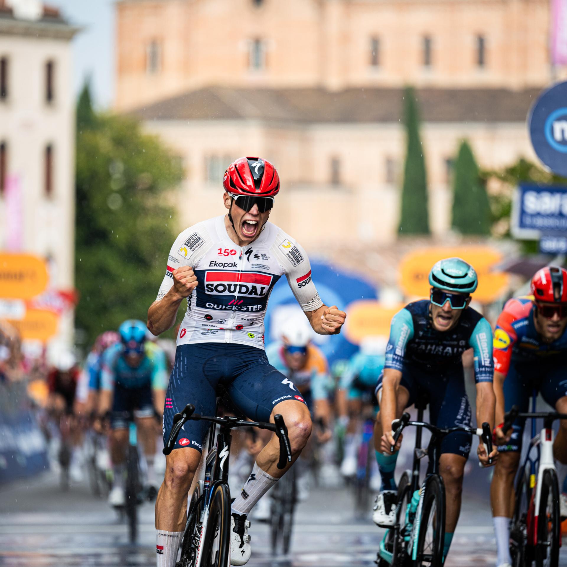 Der Franzose Paul Magnier gewinnt die 18. Etappe des Giro D'Italia. Er fährt auf seinem Rennrad durchs Ziel, ballt seine Hände zu Fäusten und freut sich.