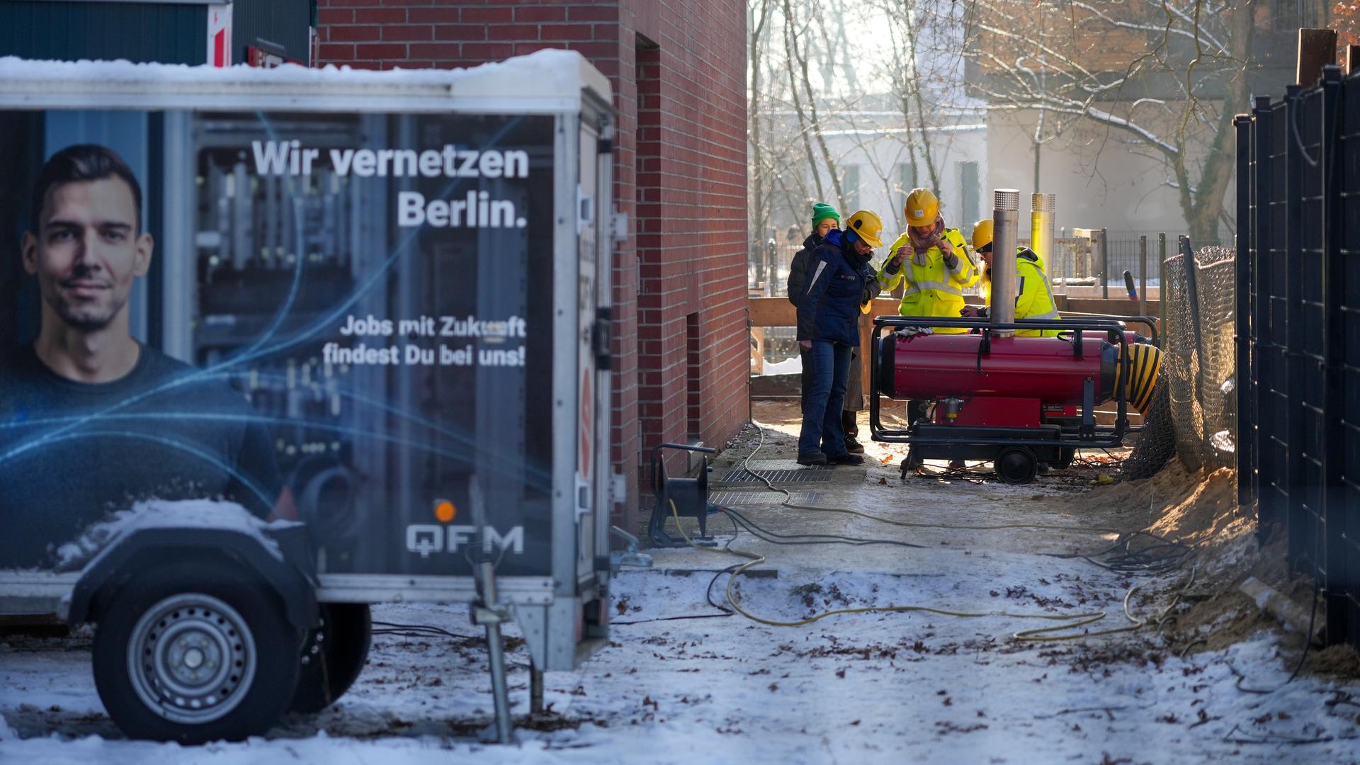 Mehrere Mitarbeiter des Umspannwerkes an der Argentinischen Allee stehen hinter einem Zaun nebeneinander. Im Vordergrund steht ein Anhänger mit der Aufschrift "Wir vernetzen Berlin". 