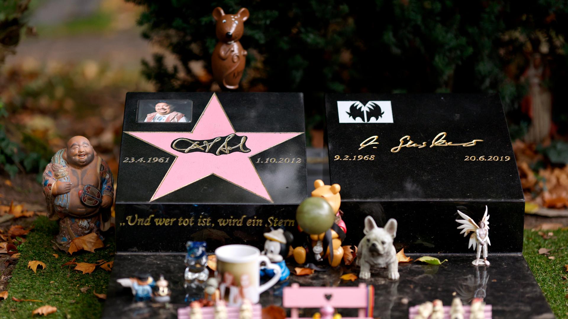 Das Grab von Entertainer Dirk Bach auf dem Melaten-Friedhof: Immer wieder bringen Fans kleine Figürchen vorbei oder haben auf einer rosa Bank am Grab eine 'Audienz beim Mausekönig'. Die Stadt Köln ließ alle Bänke entfernen. Das Grab von Entertainer Dirk Bach auf dem Melaten-Friedhof: Immer wieder bringen Fans kleine Figürchen vorbei oder haben auf einer rosa Bank am Grab eine 'Audienz beim Mausekönig'. Die Stadt Köln ließ alle Bänke entfernen.