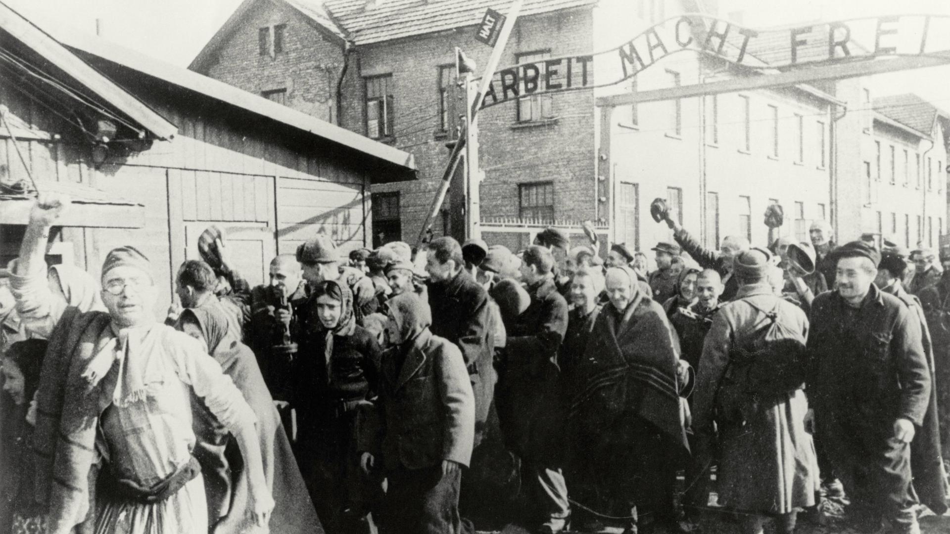 Häftlinge verlassen am 26.1.1945 das Konzentrationslager Auschwitz. Hinter ihnen das Tor auf dem "Arbeit macht frei" steht.