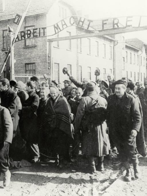 Häftlinge verlassen am 26.1.1945 das Konzentrationslager Auschwitz. Hinter ihnen das Tor auf dem "Arbeit macht frei" steht.