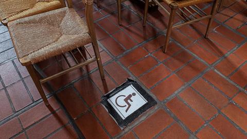 Neben einer Stuhlreihe klebt das Rollstuhlsymbol auf dem Boden in einer Kirche