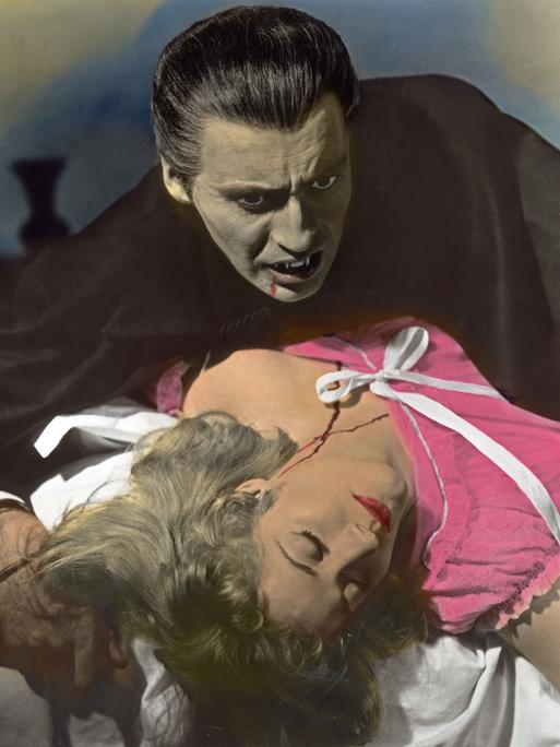 Christopher Lee als Dracula ist gerade dabei, seine Filmpartnerin, die in seinen Armen liegt, einen Biss zu versetzen