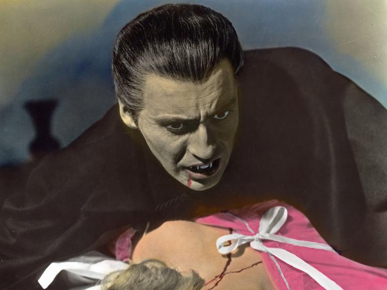 Christopher Lee als Dracula ist gerade dabei, seine Filmpartnerin, die in seinen Armen liegt, einen Biss zu versetzen
