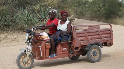 In der simbabwischen Stadt Wedza fahren zwei Frauen auf einem Tricycle.