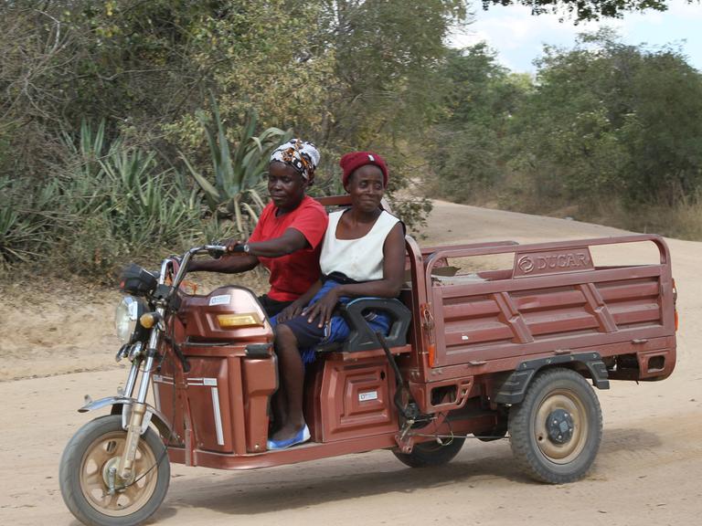 In der simbabwischen Stadt Wedza fahren zwei Frauen auf einem Tricycle.