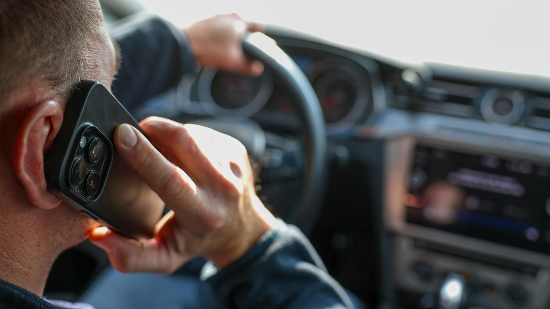 Ein Mann telefoniert in seinem Auto mit einem Smartphone. 