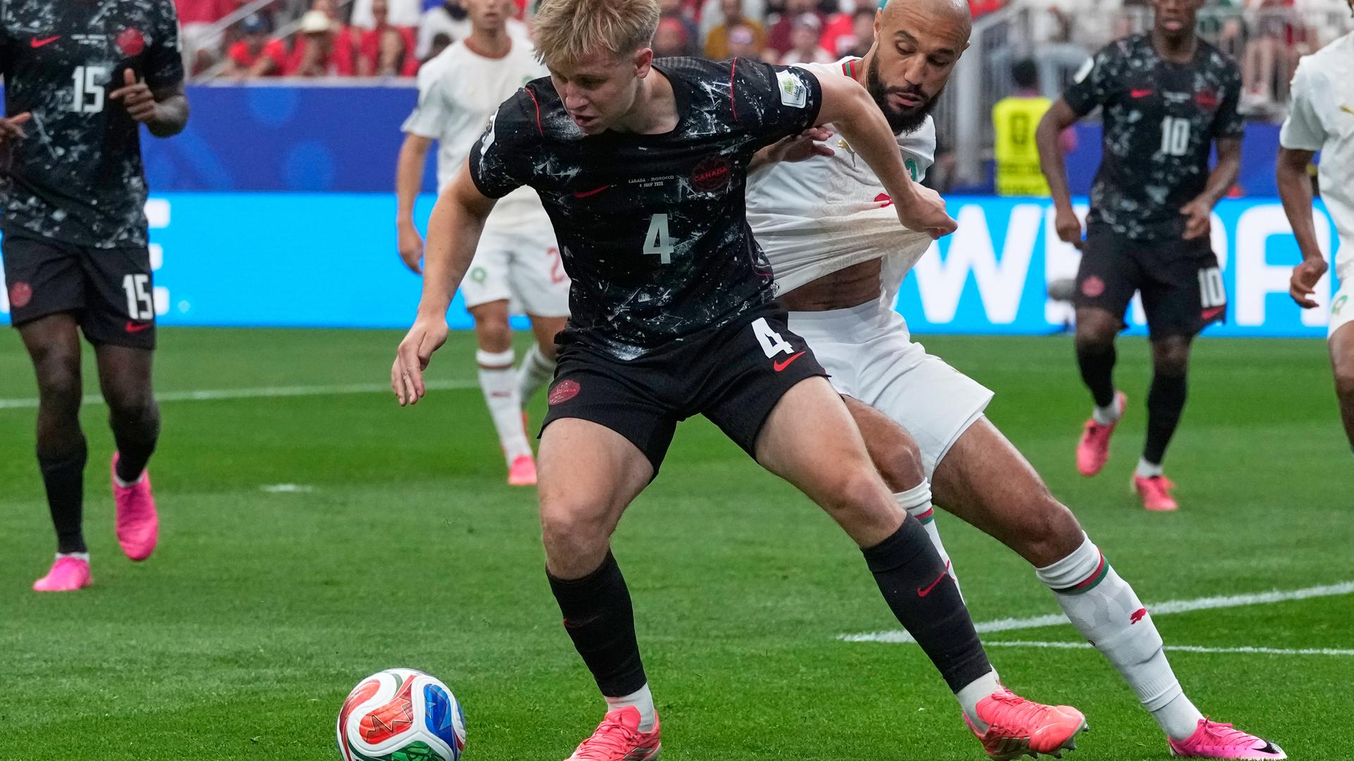 Der Kanadier Luc de Fougerolles (vorne) und der Marokkaner Noussair Mazraoui kämpfen um den Ball. Der Kanadier Luc de Fougerolles (vorne) und der Marokkaner Noussair Mazraoui kämpfen um den Ball.