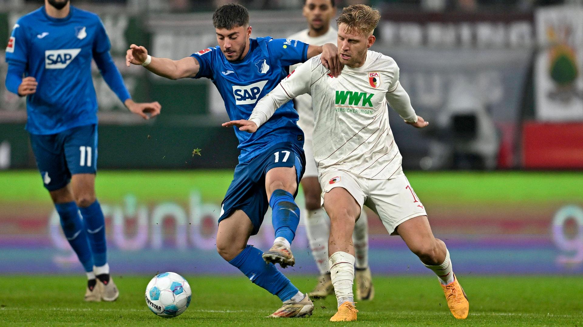 Die Fußballspieler Umut Tohumcu von der TSG 1899 Hoffenheim und Arne Maier vom FC Augsburg kämpfen um den Ball. 