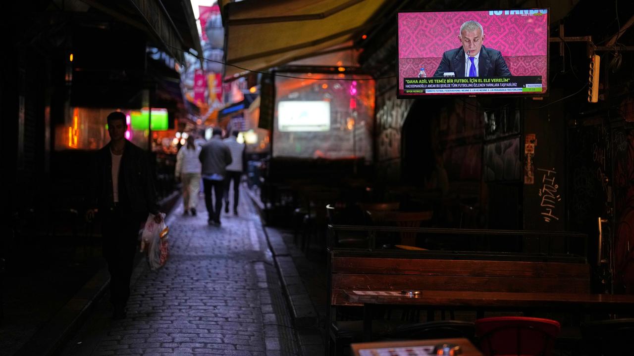 Istanbul: Menschen gehen an einem Fernsehbildschirm vorbei, auf dem der Präsident des Türkischen Fußballverbands, Ibrahim Haciosmanoglu, während einer Pressekonferenz zu sehen ist. 