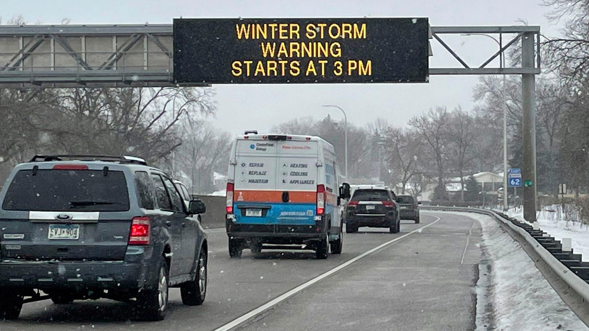 USA, Minnesota: Fahrzeuge passieren ein Schild mit der Aufschrift "WINTER STORM WARNING STARTS AT 3PM" USA, Minnesota: Fahrzeuge passieren ein Schild mit der Aufschrift "WINTER STORM WARNING STARTS AT 3PM"