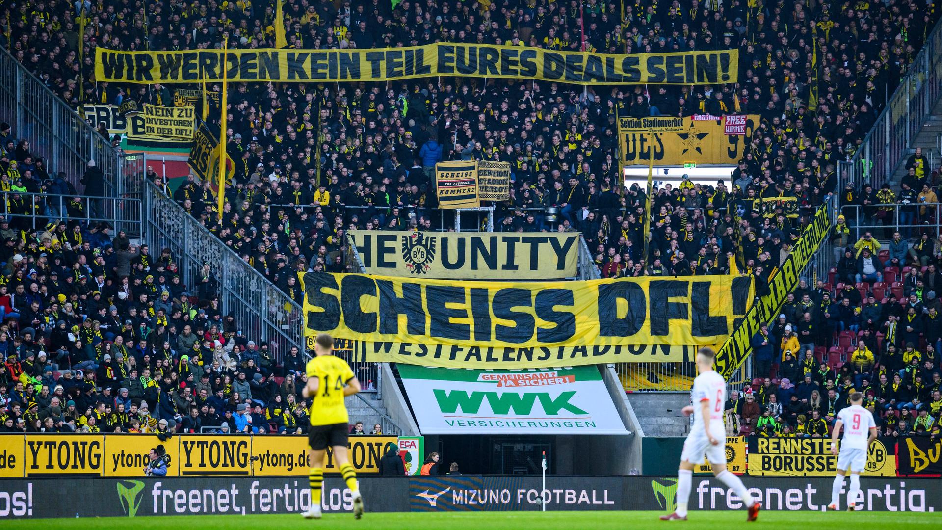 Fans von Borussia Dortmund haltenbeim Spiel FC Augsburg - Borussia Dortmund ein Banner mit der Aufschrift "Wir werden kein Teil eures Deals sein! Scheiss DFL" in die Luft.