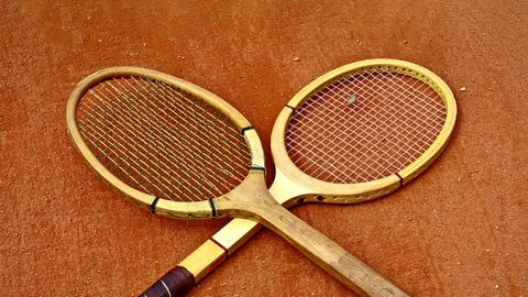 Zwei historische Tennisschläger, die überkreuzt liegen.