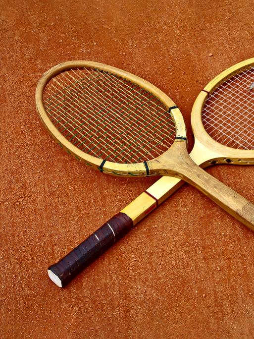 Zwei historische Tennisschläger, die überkreuzt liegen. Zwei historische Tennisschläger, die überkreuzt liegen.