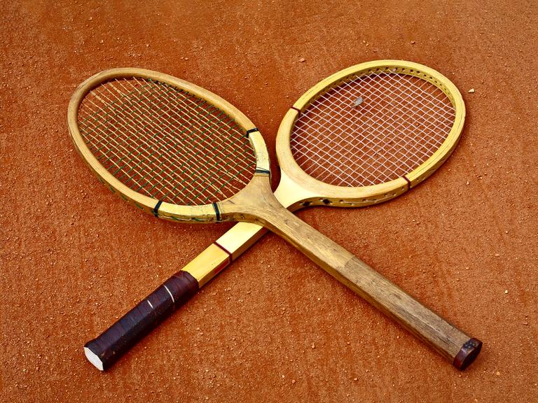 Zwei historische Tennisschläger, die überkreuzt liegen. Zwei historische Tennisschläger, die überkreuzt liegen.