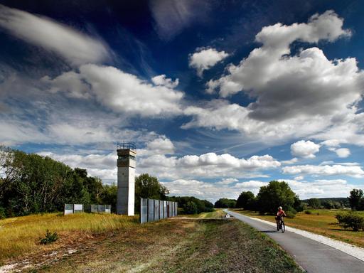 Eine Radfahrerin fährt an einem ehemaligen Beobachtungsturm der Grenztruppen der DDR auf dem Elbradwanderweg vorbei