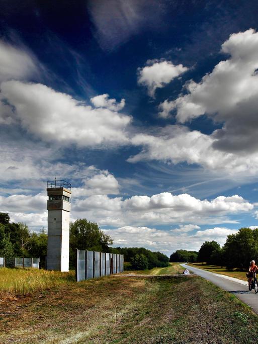 Eine Radfahrerin fährt an einem ehemaligen Beobachtungsturm der Grenztruppen der DDR auf dem Elbradwanderweg vorbei