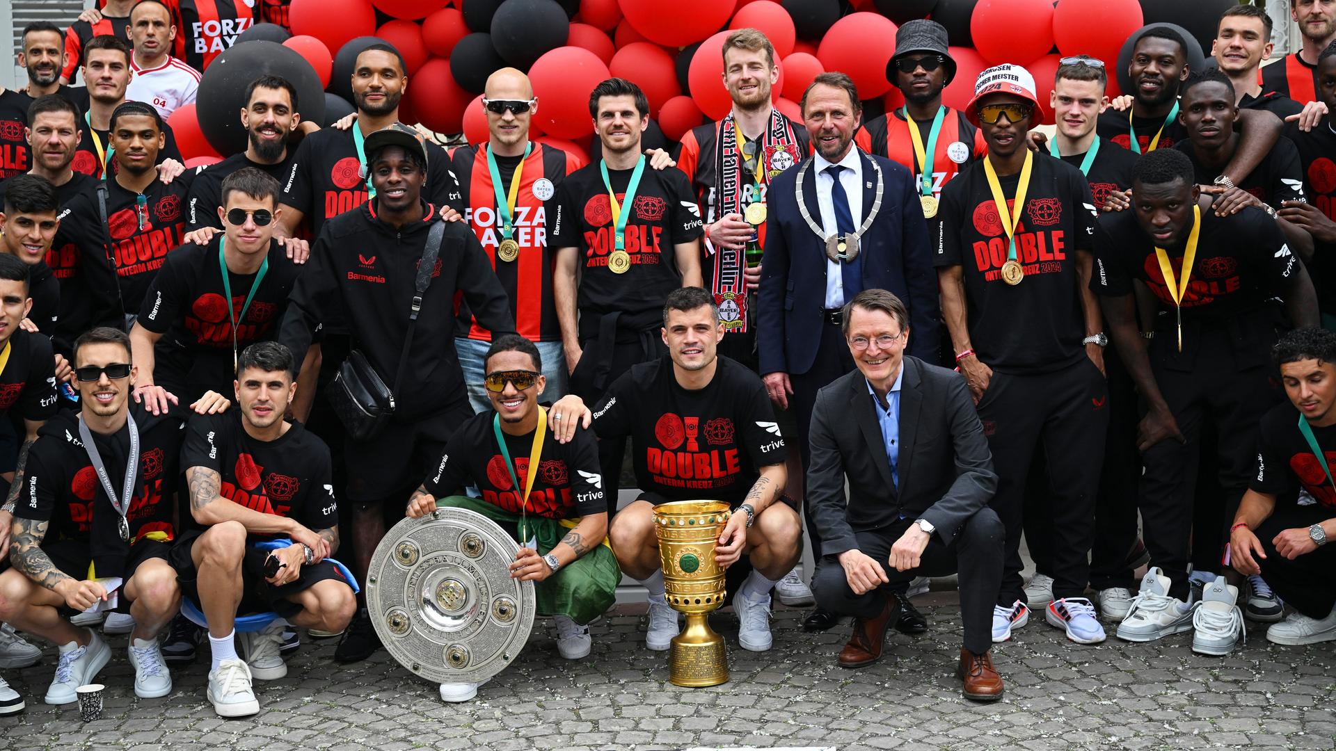 Das Foto zeigt die Mannschaft von Bayer Leverkusen mit der Meister-Schale und dem DFB-Pokal.