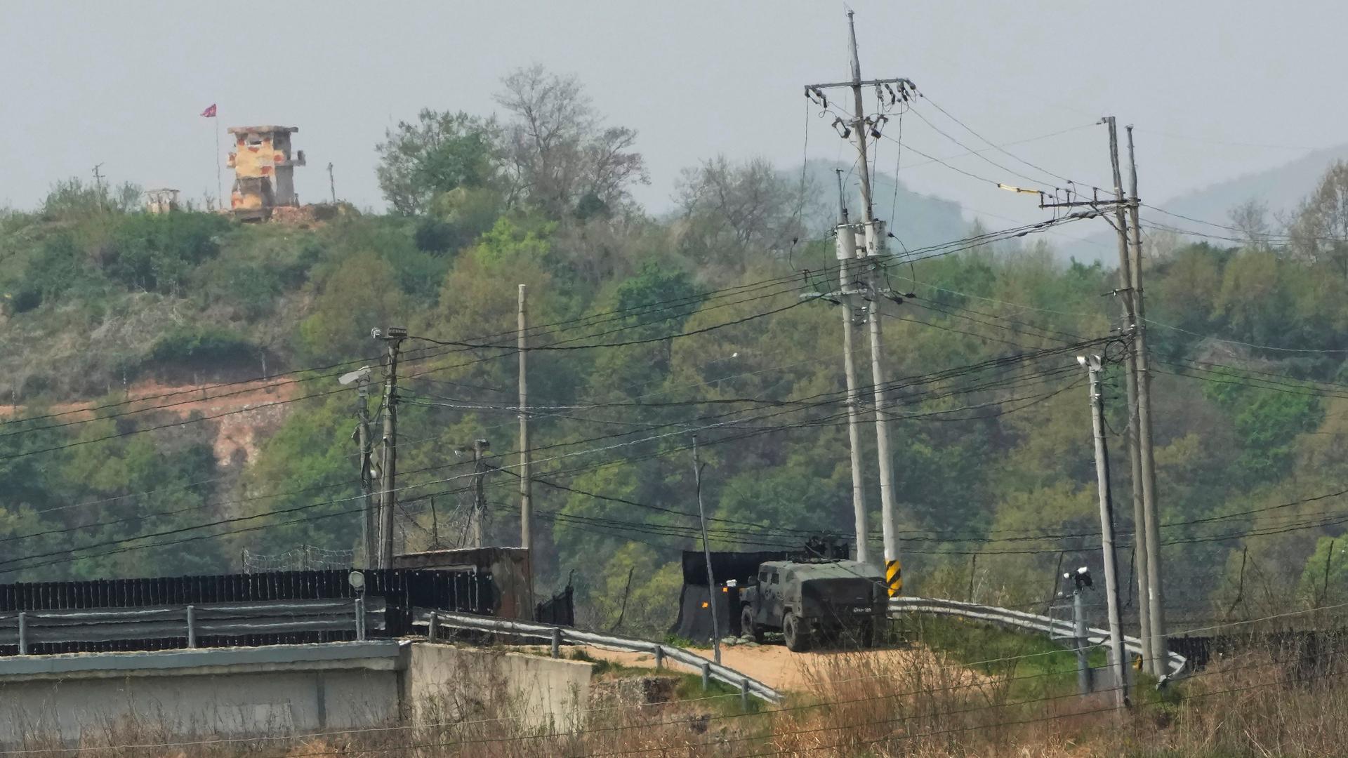 Südkorea, Paju: Ein leicht gepanzerter Spähwagen (r) fährt auf der südkoreanischen Seite an der Grenze zu Nordkorea, während ein militärischer Wachposten Nordkoreas (oben, l) zu sehen ist. Südkorea, Paju: Ein leicht gepanzerter Spähwagen (r) fährt auf der südkoreanischen Seite an der Grenze zu Nordkorea, während ein militärischer Wachposten Nordkoreas (oben, l) zu sehen ist.