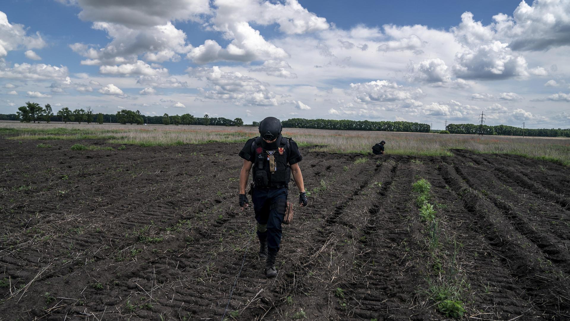 Ein Entminungsteam führt Kontrollen auf einem landwirtschaftlichen Feld vor.