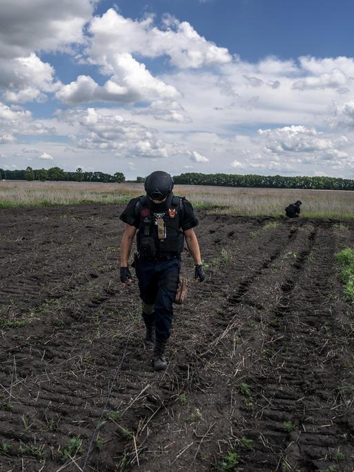 Ein Entminungsteam führt Kontrollen auf einem landwirtschaftlichen Feld vor.