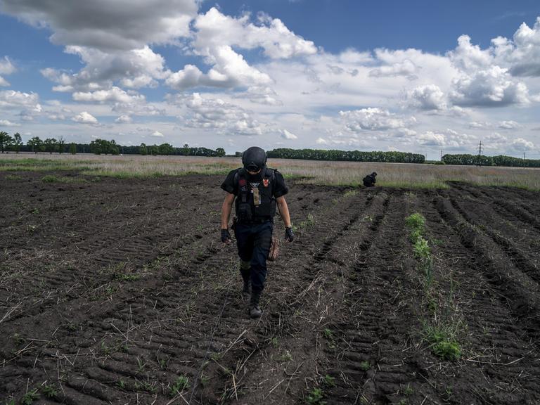 Ein Entminungsteam führt Kontrollen auf einem landwirtschaftlichen Feld vor.