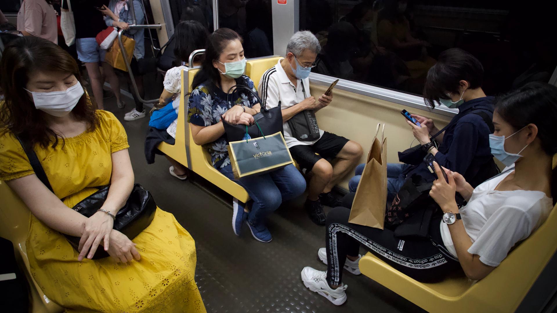 Fahrgäste in der U-Bahn von Taipeh. Die meisten tragen Masken und schauen auf ihre Smartphones.