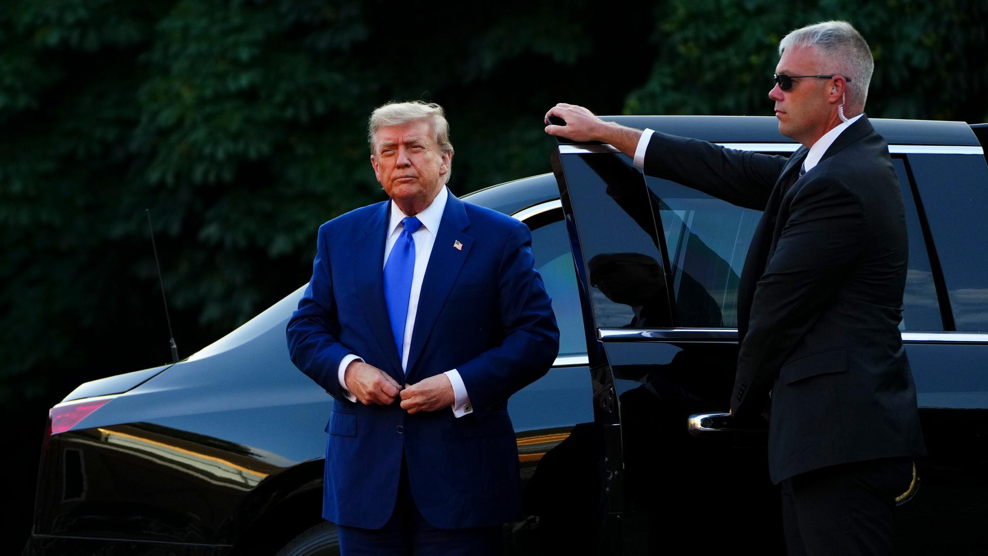 US-Präsident Donald Trump steigt in einem dunkelblauen Anzug aus einem schwarzen Auto.