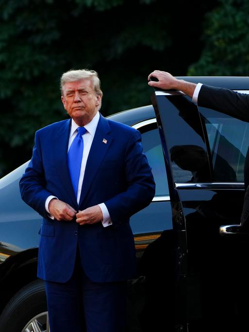 US-Präsident Donald Trump steigt in einem dunkelblauen Anzug aus einem schwarzen Auto.