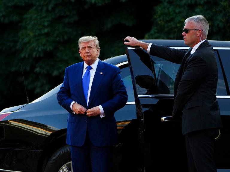 US-Präsident Donald Trump steigt in einem dunkelblauen Anzug aus einem schwarzen Auto.