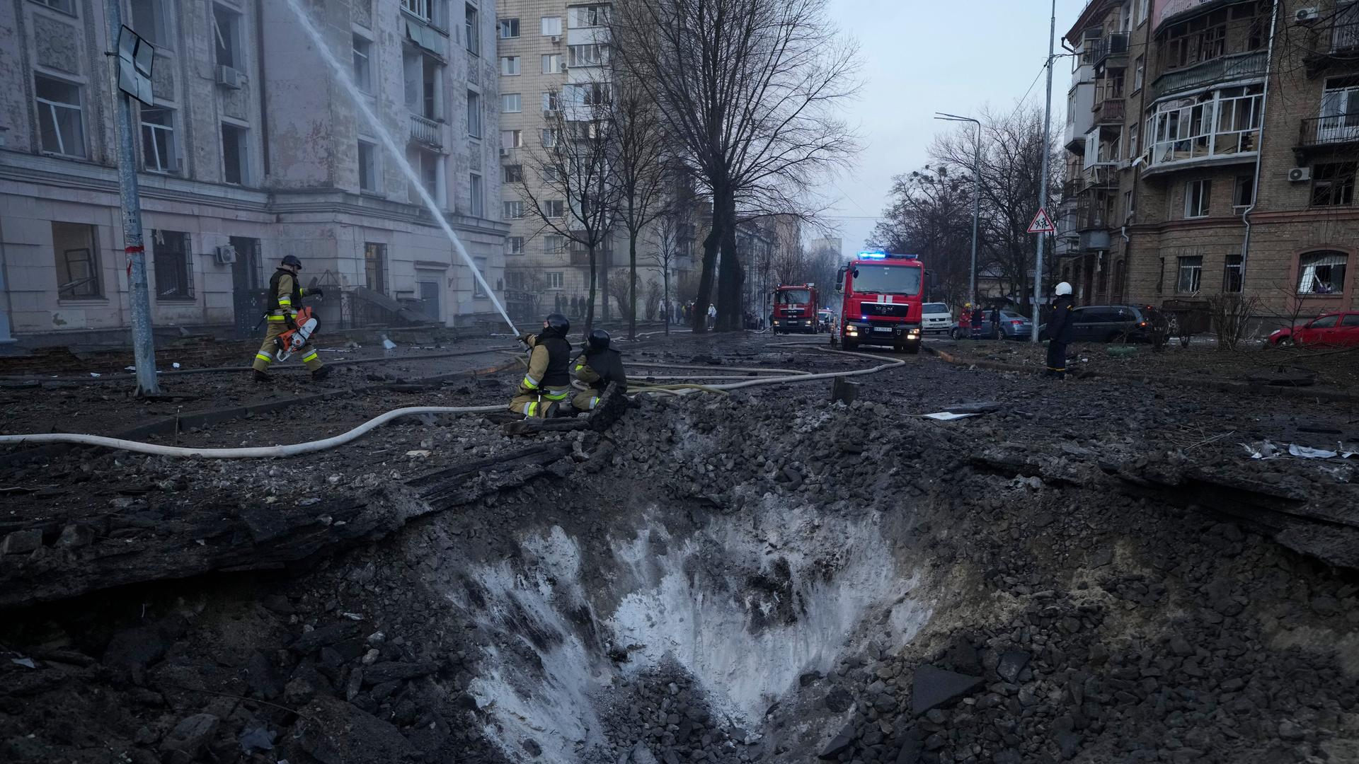 Ukraine, Kiew: Feuerwehrleute arbeiten in der Nähe eines Kraters nach russischen Angriffen.