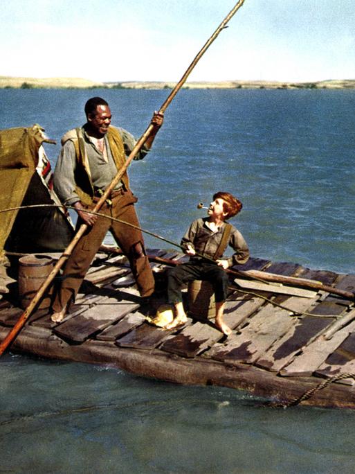 In der Verfilmung von "Die Abenteuer des Huckleberry Finn" steht der entflohene Sklave mit einem Stechpaddel auf einem Floß im Mississippi. Neben ihm der Junge Huckleberry Finn mit einer Pfeife im Mund und einer Angelrute in der Hand.