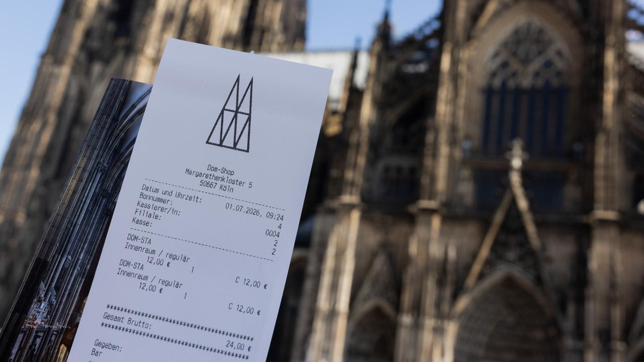 Eine Touristin zeigt ihr Ticket vor dem Kölner Dom. 