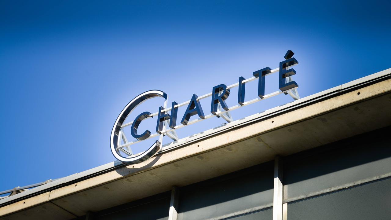 Schriftzug "Charite" auf einem Gebäude bei blauem Himmel von unten fotografiert. 