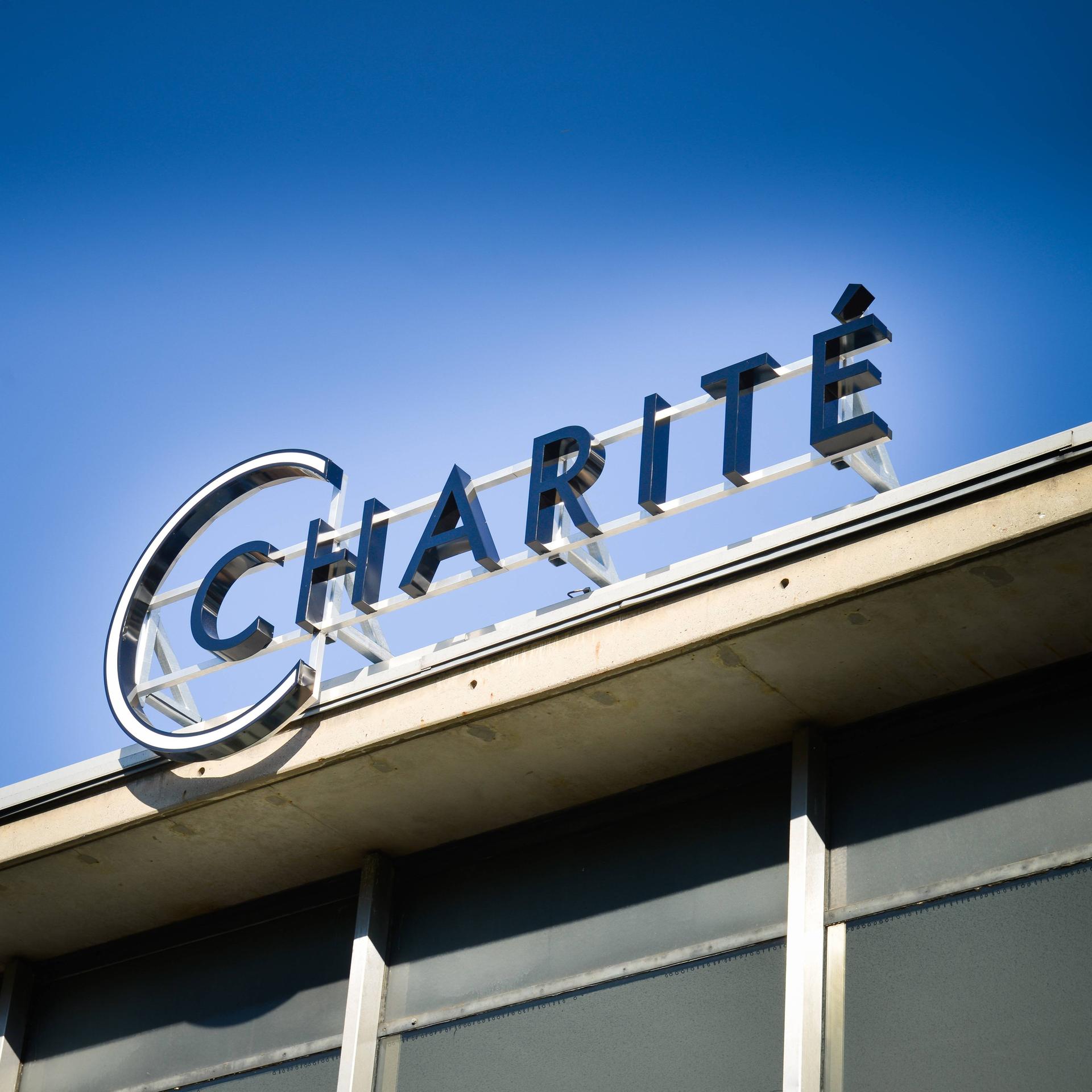 Schriftzug "Charite" auf einem Gebäude bei blauem Himmel von unten fotografiert. 