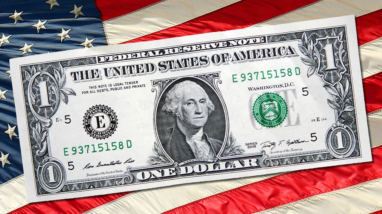 Eine Dollar-Note vor einer US-Fahne 