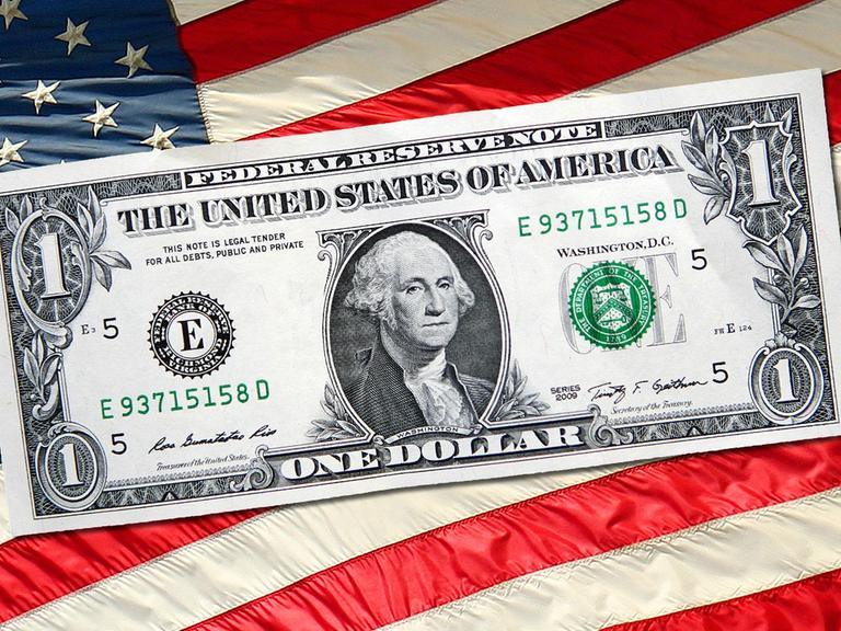 Eine Dollar-Note vor einer US-Fahne 
