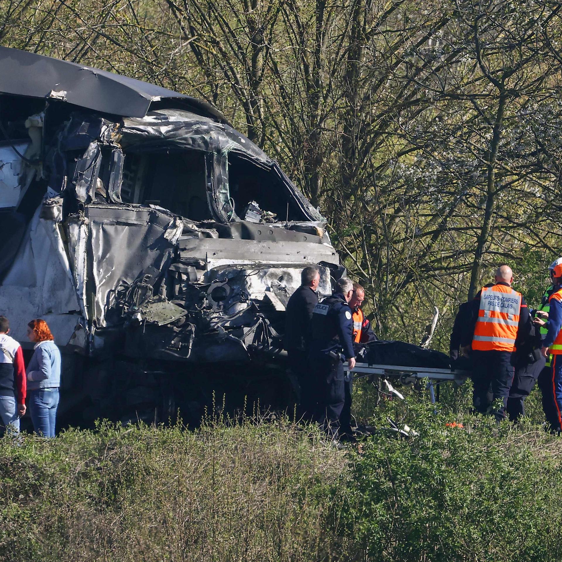 Feuerwehrleute und Polizisten transportieren eine Person aus dem Wrack eines TGV-Zuges auf einem Bahnübergang zwischen Bethune und Lens in Bully-les-Mines.